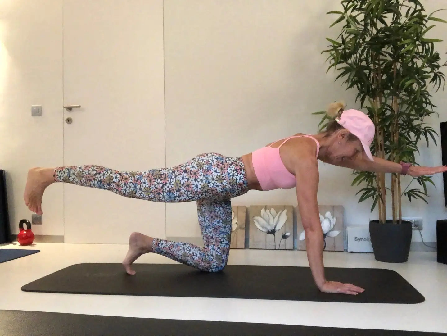 Soutien-gorge de sport rose avec leggings floraux et casquette assortie.